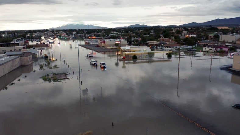 A flooded street with several cars and businesses submerged