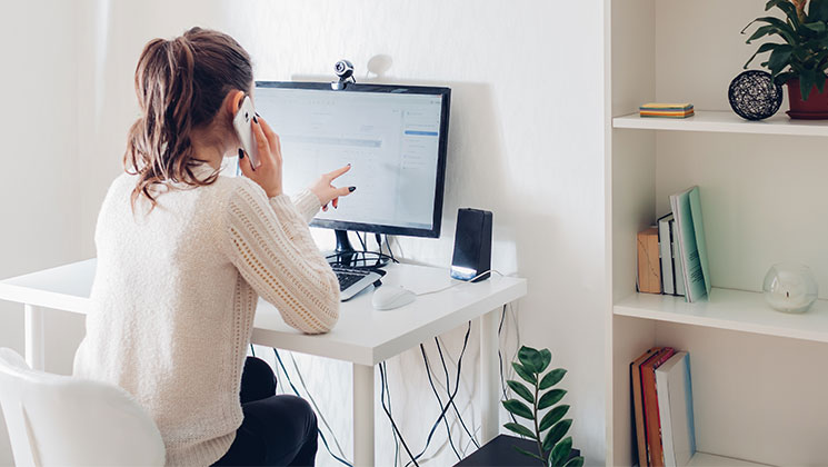 A person working from home at a desk with a webcam