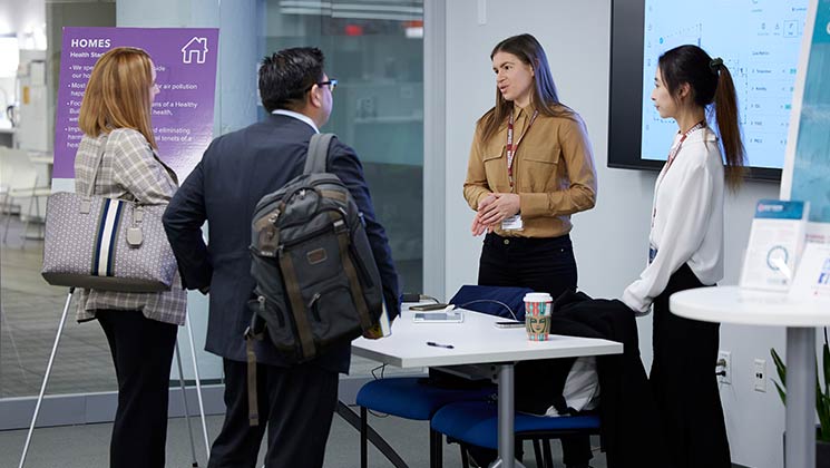 Two researchers at a table answering questions with two visitors