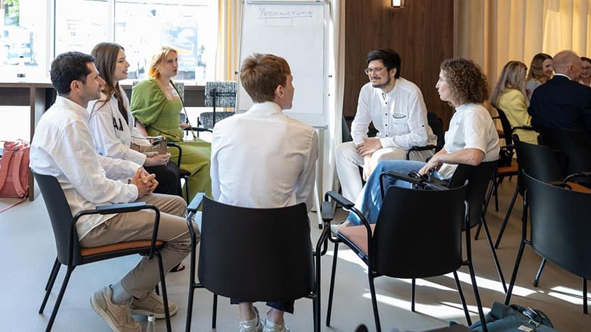 Group of students in a circle of chairs discussing course material